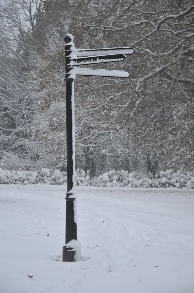 Snow-covered signpost beside a quiet path