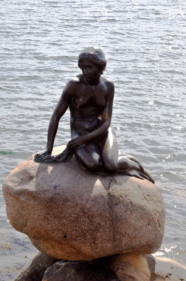 A bronze figure sculpture beside the water
