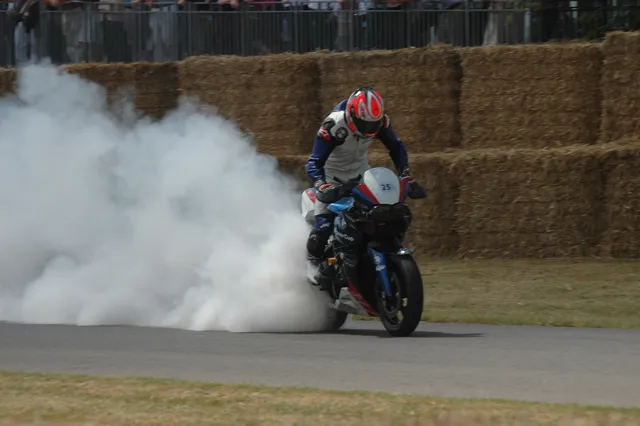 A motorcycle racer riding through a cloud of track smoke