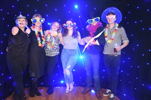 A group of guests posing together under blue lights
